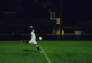 person kicks soccer ball in field